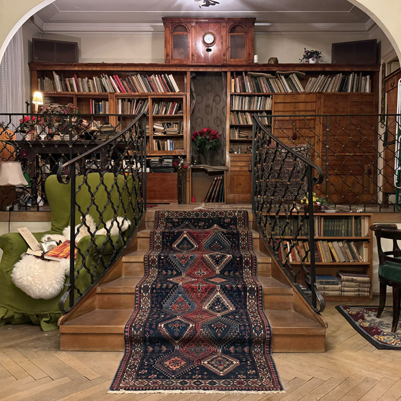 Vorher: Vollständig möblierter Wohnbereich mit großer Bibliothek, Teppichen und Dekoration vor der Verlassenschaftsräumung in Wien.