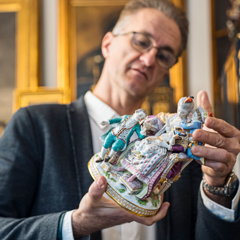 Experte Haldenwang prüft die Bodenmarke einer antiken Porzellanfigur zur Wertermittlung – Ankauf von Meissen, Augarten und Herend Porzellan in Wien.