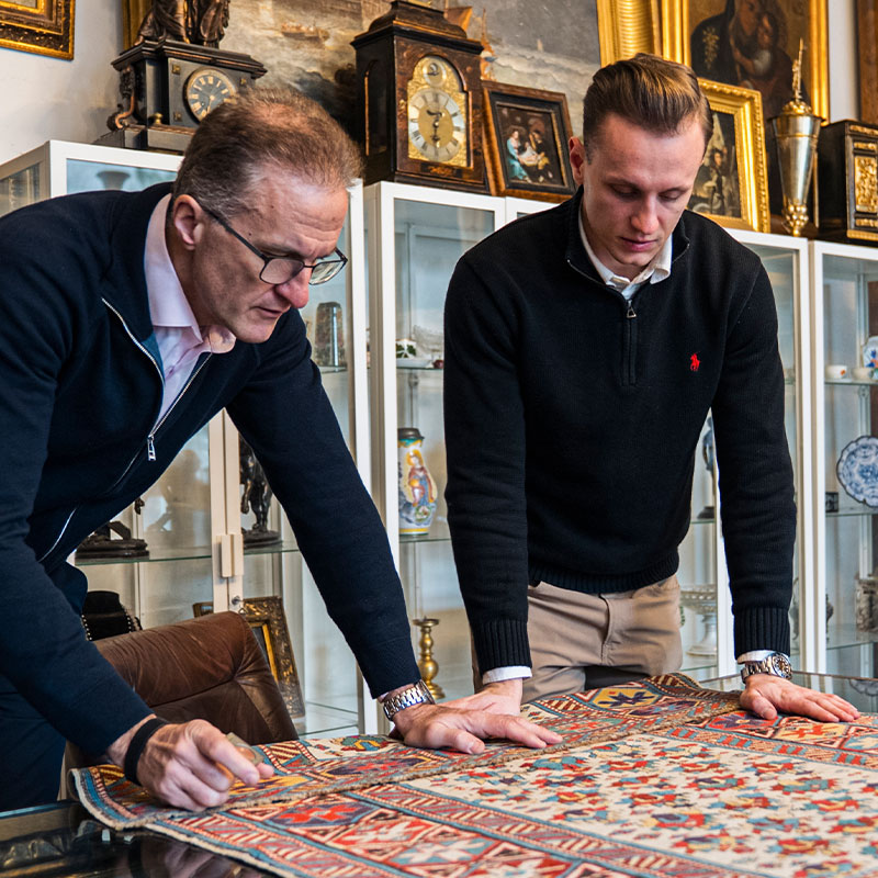 Experte für antike Teppiche Ankauf Wien: Fachmännische Begutachtung von Knüpfdichte, Flor und Herkunft eines antiken Perserteppichs zur Wertermittlung.